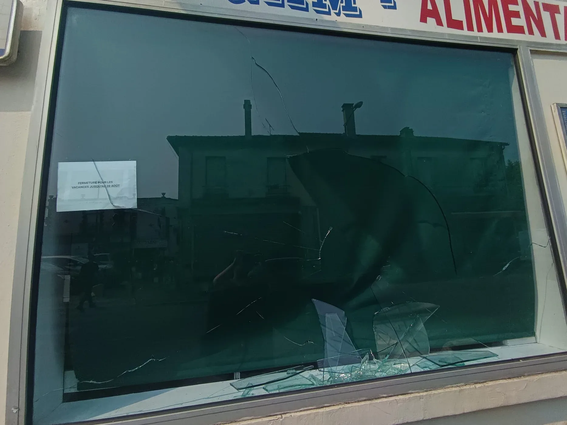 Vitrine d'épicerie fissurée et bâchée après un sinistre